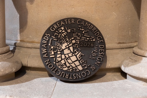 A close-up view of the circular Greater Cambridge Design and Construction Awards 2026 plaque, featuring a raised map-style pattern in the centre and engraved text around the edge.